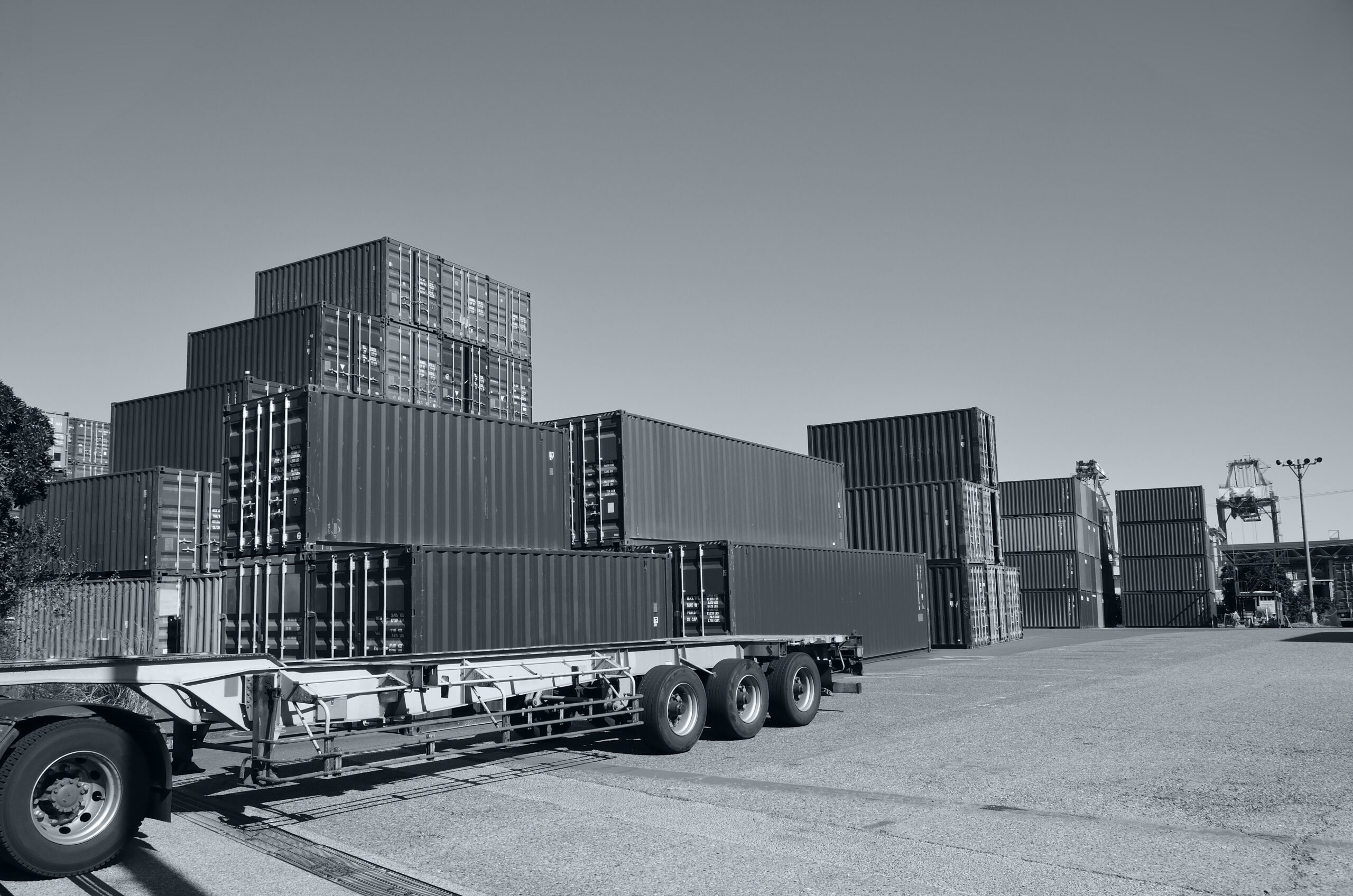 Shipping containers stacked near flatbed trailer at port logistics hub