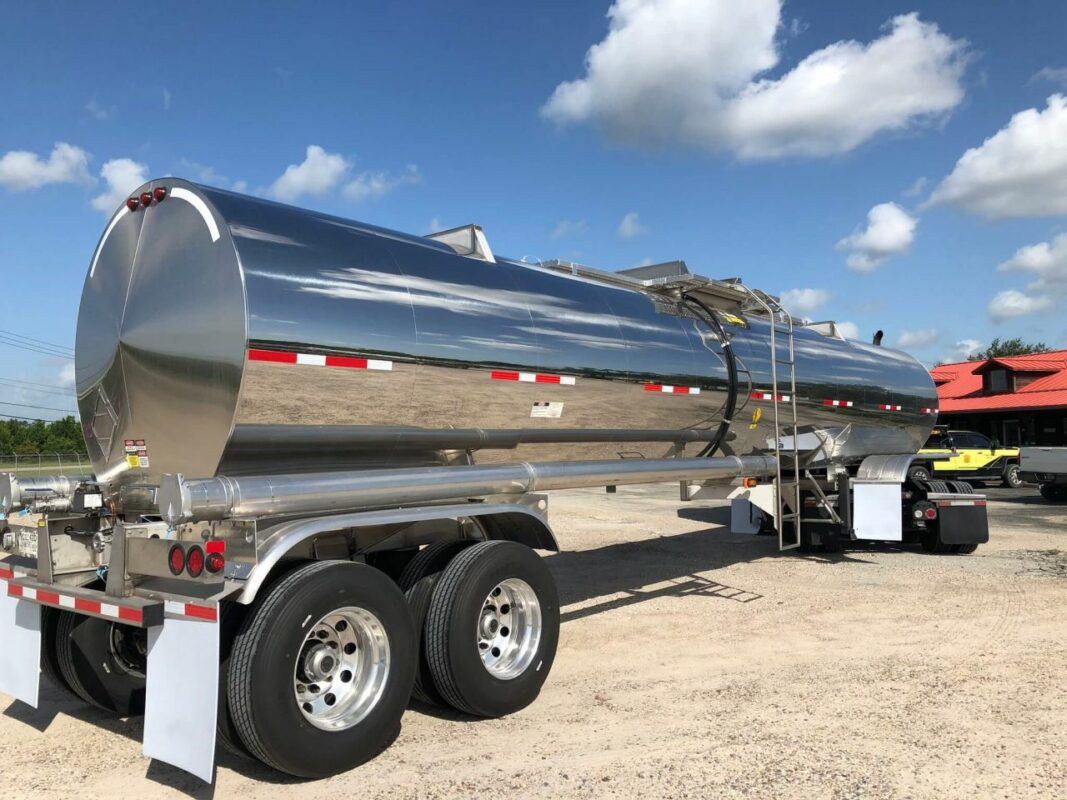Polished stainless steel tanker trailer under blue sky